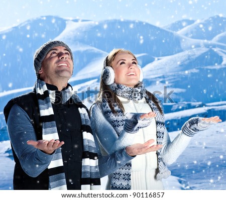 Happy couple playing outdoor at winter mountains, active people over natural blue wintertime landscape background with falling snow, Christmas vacation holidays