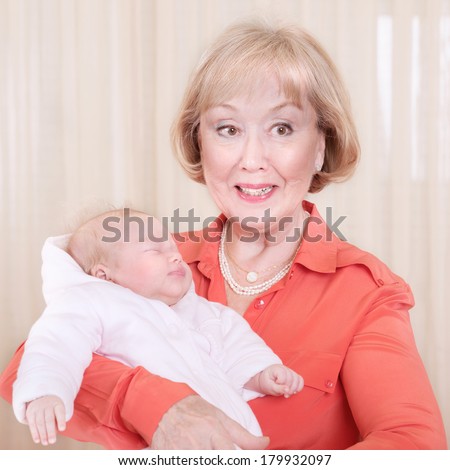 Grandmother with baby on hands at home, elegant young granny having fun with grandchild, happy family generation, new life concept