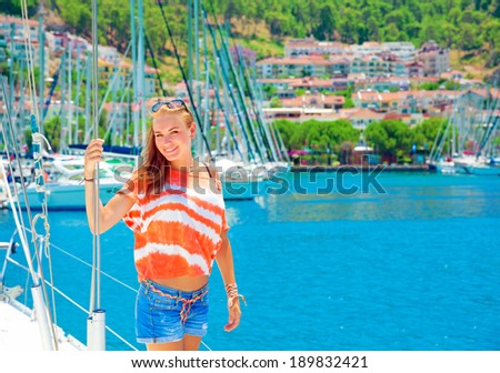 Cute girl having fun in yacht harbor, enjoying sunny summer day, active lifestyle, traveling on luxury water transport