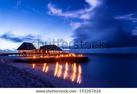Romantic restaurant on the beach, beautiful night seascape, luxury resort on Maldives, dark blue sky, summer vacation concept
