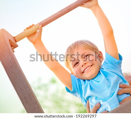 Little boy with fathers help catch up on the horizontal  bar, active childhood, cute small acrobat, workout on backyard, summer camp concept