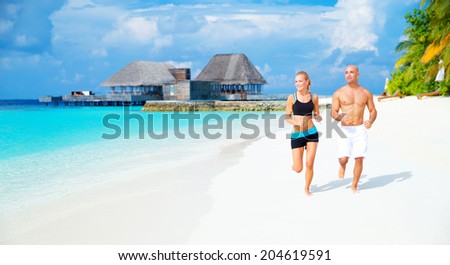 Happy couple jogging on white sandy beach on luxury Maldives resort, workout outdoors, healthy lifestyle, active summer time