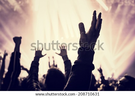 Grunge style photo of silhouette of people hands raised up on musical concert, enjoying music, dance club, active night life concept