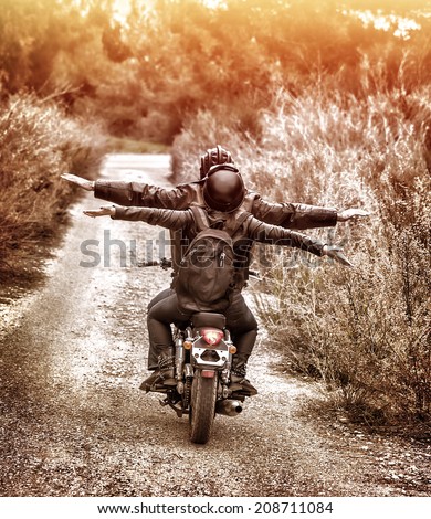 Vintage style image, rear view of two happy bikers riding on the road with raised up hands, active family enjoying journey on luxury extreme transport, freedom concept