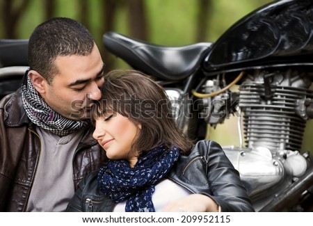 Attractive woman sleeping on shoulders of her husband, sitting near bike, relaxation after bikers tour in the forest, active and loving family concept