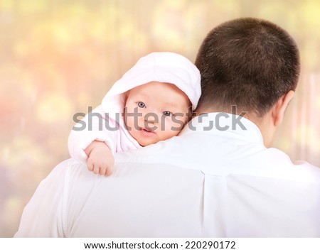 Portrait of father with baby at home, back side of happy young daddy holding newborn child on hands over blur bokeh background, loving family concept