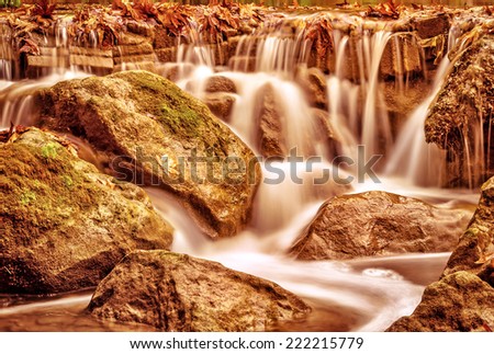 Beautiful waterfall landscape, wild river streaming through stones in mountainous forest, majestic scene, autumn nature concept