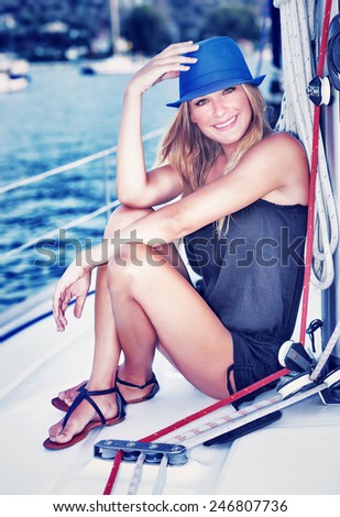 Pretty woman relaxing on luxury sailboat, sitting on the deck and enjoying leisure time in the sea, happy summer vacation concept