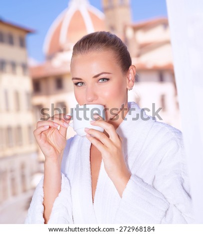 Portrait of a beautiful woman having morning tea in hotel room in Florence, Italy, Europe, standing on the balcony over  wonderful cityscape background
