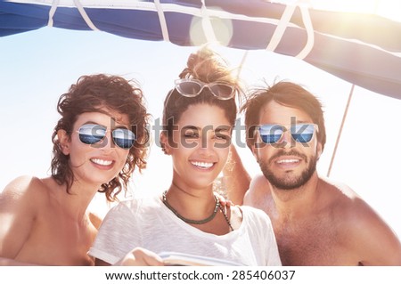 Portrait of happy three people having fun on sailboat, best friends traveling together, enjoying bright sunny summer days in sea cruise