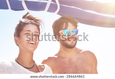Portrait of handsome guy and beautiful woman having fun on sailboat in sunny day, best friends spending summer vacation in the sea cruise