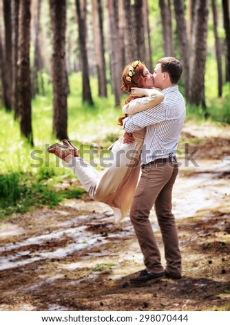 Happy couple in the forest, having fun outdoors in wedding day, groom lifted and whirls his lovely bride, enjoying romantic relationship