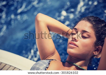 Closeup portrait of beautiful seductive woman with closed eyes tanning on the deck of the sailboat, with pleasure spending summer vacation in the sea