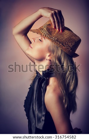 Side view of beautiful woman dancing in night club, closing eyes of pleasure, wearing stylish shiny hat, celebrating new year holiday