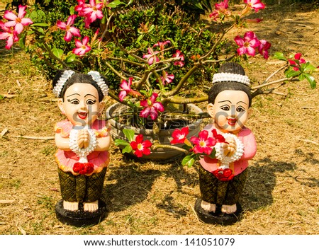 thai children figure in the garden with desert rose