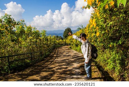 Asian man hitchhiking  on the flower field road.