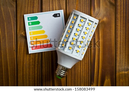 top view of LED lightbulb with energy label on wooden background