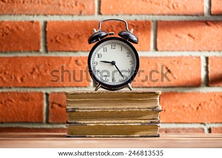 The old clock and books in front of a brick wall