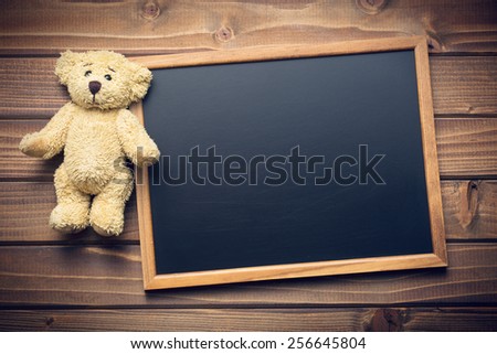blank chalkboard and teddy bear on wooden table