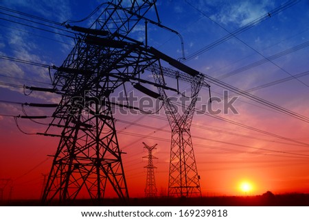 Many high voltage towers under the setting sun exposure in the field