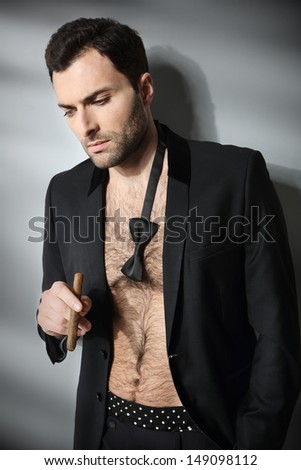 Sexy male model smoking cigar in open formal attire
