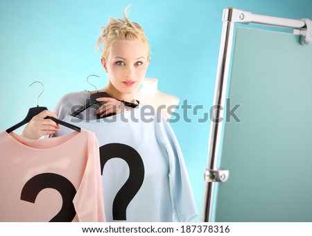 Shopping dilemmas - a woman in dressing room . Woman shopping wonders blue or pink blouse