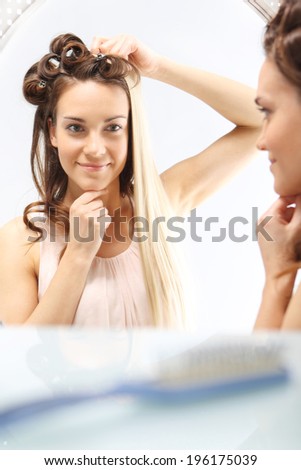 Brunette or blonde?  Woman with hair standing in front of a mirror. Changing hair color. Full colored hair.