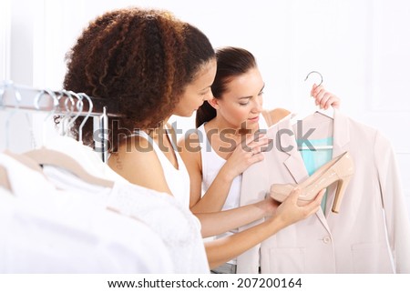 Two women shopping in boutique clothing, mulatto and Caucasian
