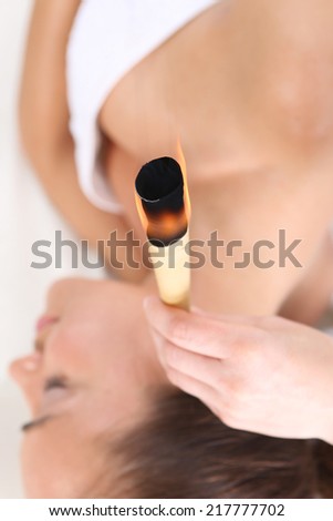 Purification of the ears, a natural spa treatment .Woman relaxes in the study of natural medicine. ear candling treatment