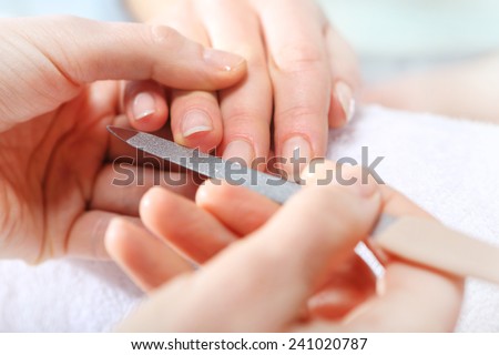 Nail sawing a woman in a beautician. Treatment hand and nail care, the woman to a beautician for a manicure.