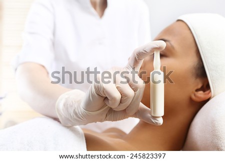 Cosmetic ampoule, serum applied to the face of a woman. Hand beauticians shows an ampoule with a cosmetic preparation