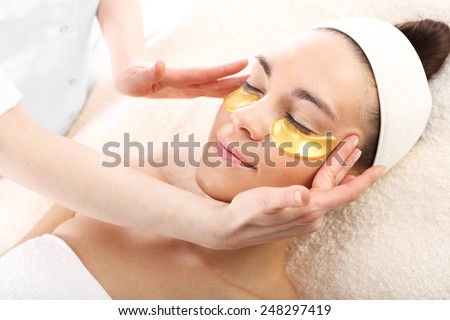 Acupressure, massage his temples, golden flakes collagen.Cosmetic procedure, the woman\'s face with gold flakes under the eyes and on the lips