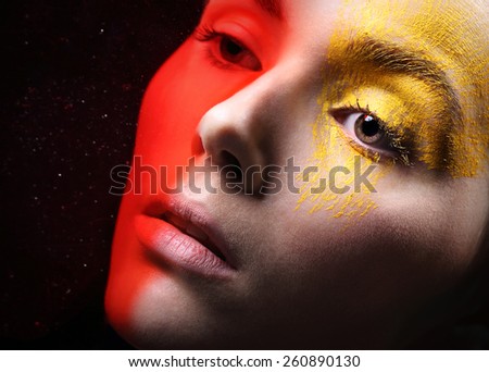 Hot red, sunny yellow, fancy makeup .Portrait, close-up on the face of a woman in a fancy makeup.