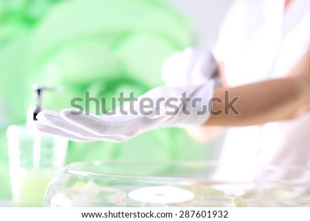 Paraffin hand treatment, beauty salon. The woman assumes cotton gloves after applying wax