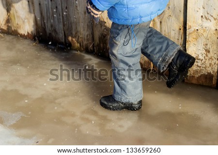 child in black leather boots running on slippery roads