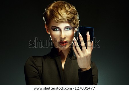 Portrait of a beautiful woman looking into mirror, isolated on dark background