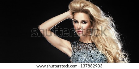 Sensual portrait of elegant young blonde woman looking at camera. Long curly hair, diamond dress.