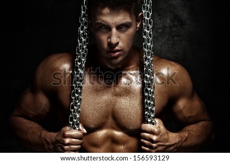 Handsome young man posing with metal chain. Perfect body.
