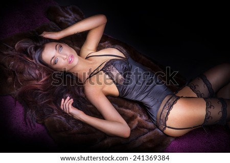 Sexy brunette woman posing in elegant lingerie, looking at camera. Girl with perfect body lying, relaxing.