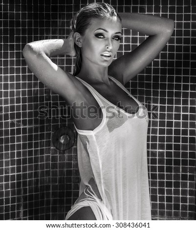 Sexy beautiful blonde woman posing wet, looking at camera.