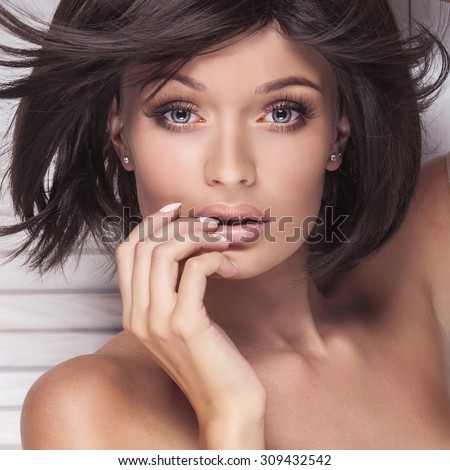 Closeup beauty portrait of sexy brunette woman with long lashes and short hair. Girl looking at camera. Perfect skin. Beautiful eyes. Studio shot.