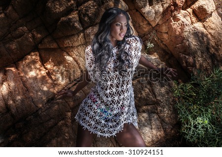 Sexy african american woman posing outdoor. Girl with long curly hair, looking away.