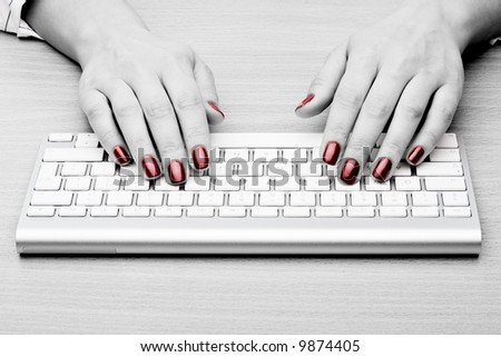 Fingers with red nail typing on keyboard