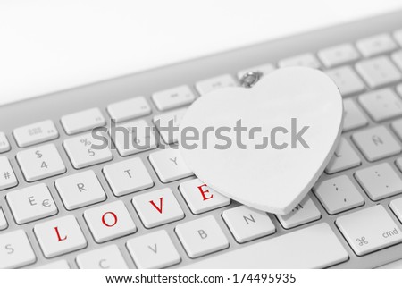 Heart over white keyboard with the word love.  Love concept