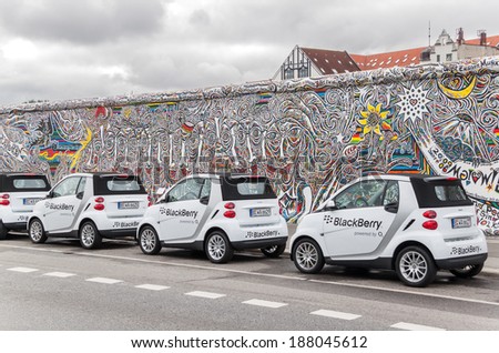 BERLIN, GERMANY-AUGUST 30,2010: Mercedes Smart cars in front of Berlin Wall. Mercedes and  Black Berri companies cooperate many years in various spheres such as the preparation of sport cars Formula1.