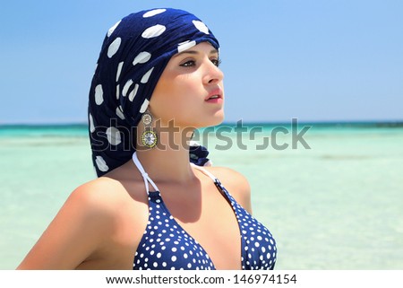 beautiful woman in a blue scarf on the beach. blue bikini. arabic style