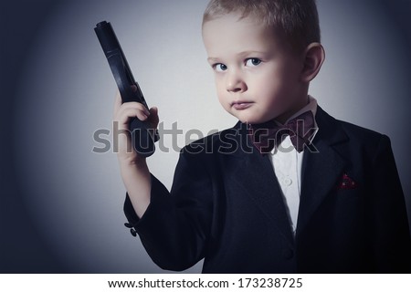 Handsome Boy with Gun.Fashionable Boy in Suit .Stylish Agent. Fashion Children.Child in Bow tie. Elegance. Little James Bond