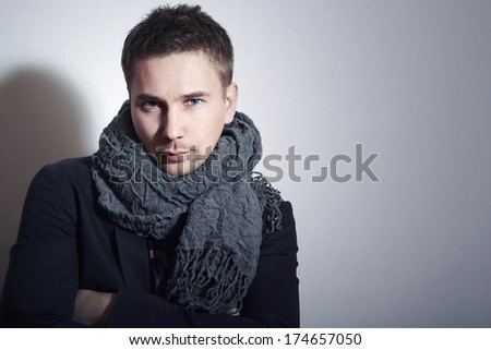 Fashionable Handsome Man in Scurf. Stylish Boy with Blue Eyes. Casual Winter Fashion. Grey Background