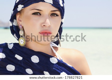 Beautiful Woman in Blue Scarf on the Beach. Arab Fashion. Blue Sea Landscape. Summer
