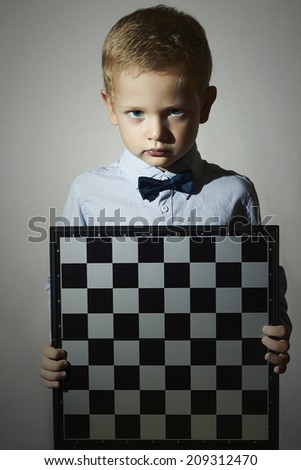 Little boy with chessboard.fashion children.Bow-tie.Little genius Child. Intelligent game.Emotion. Serious